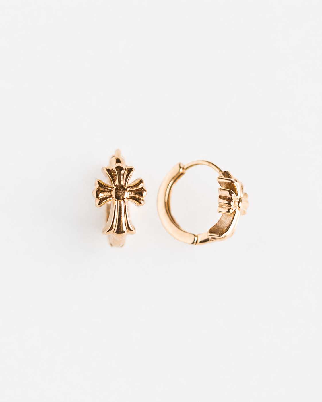 Gold cross earring and hoop earring on a white background