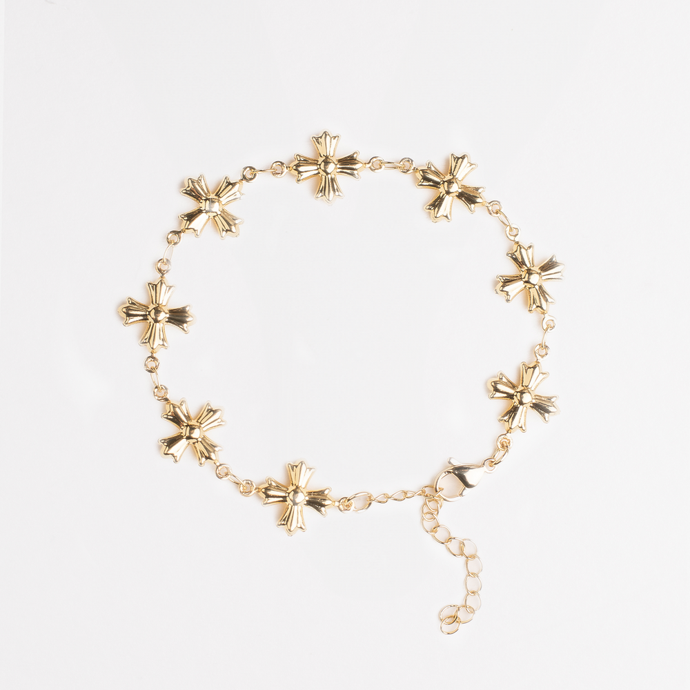 Gold bracelet with vintage cross design on a white background