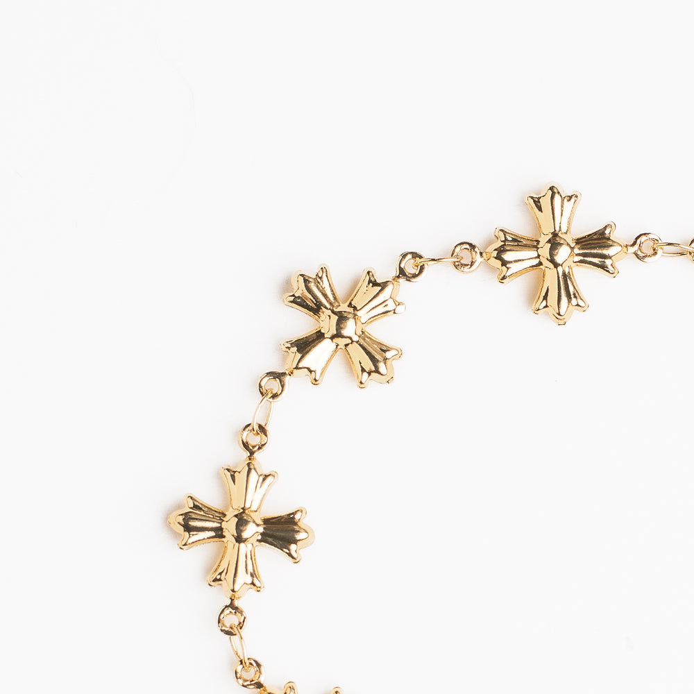 
                  
                    Gold bracelet with cross shaped links on a white background
                  
                
