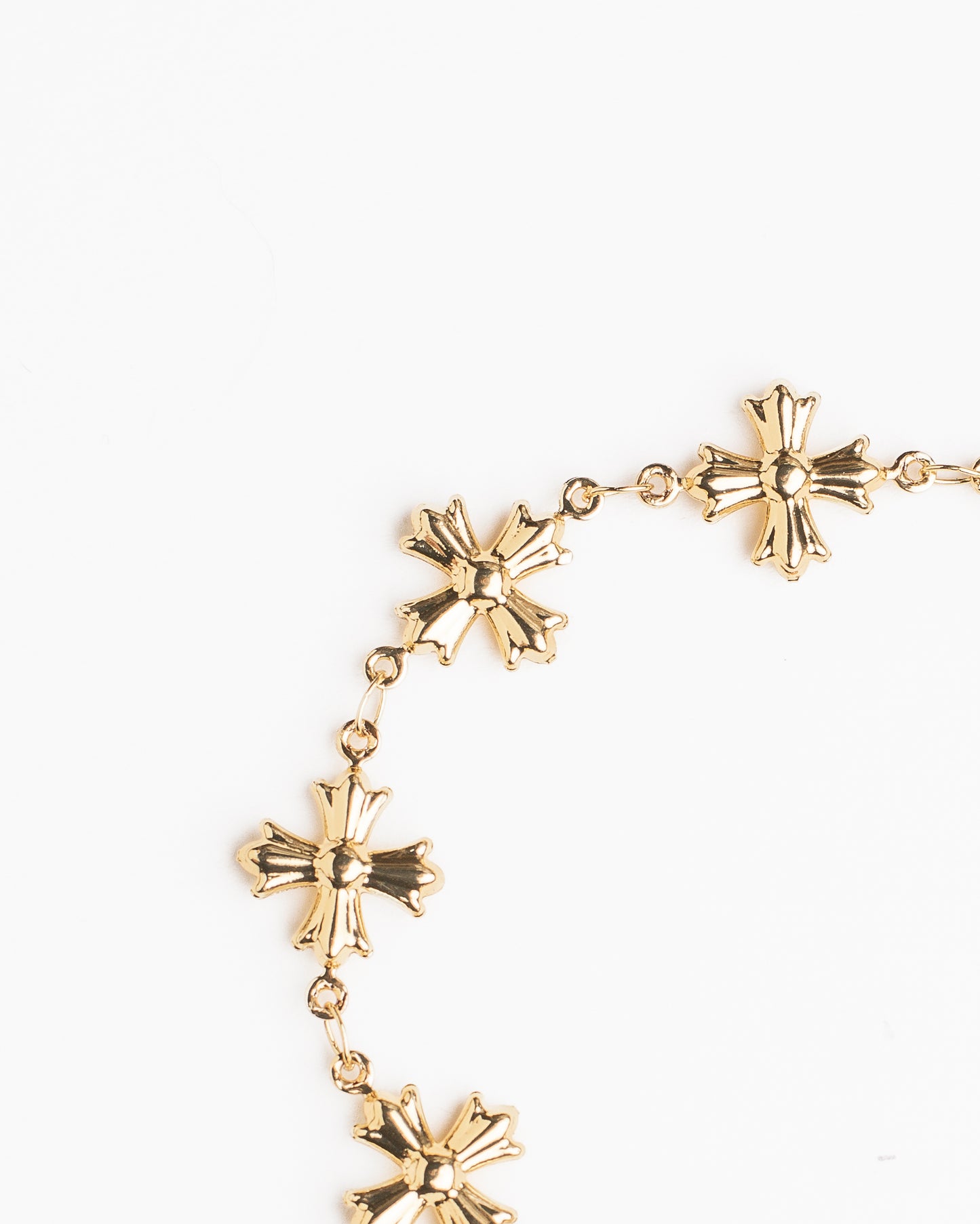 Gold bracelet with cross shaped links on a white background