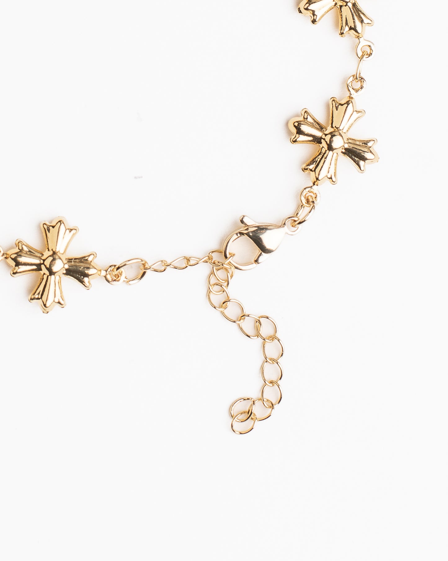 Gold bracelet with cross shaped charms on a white background