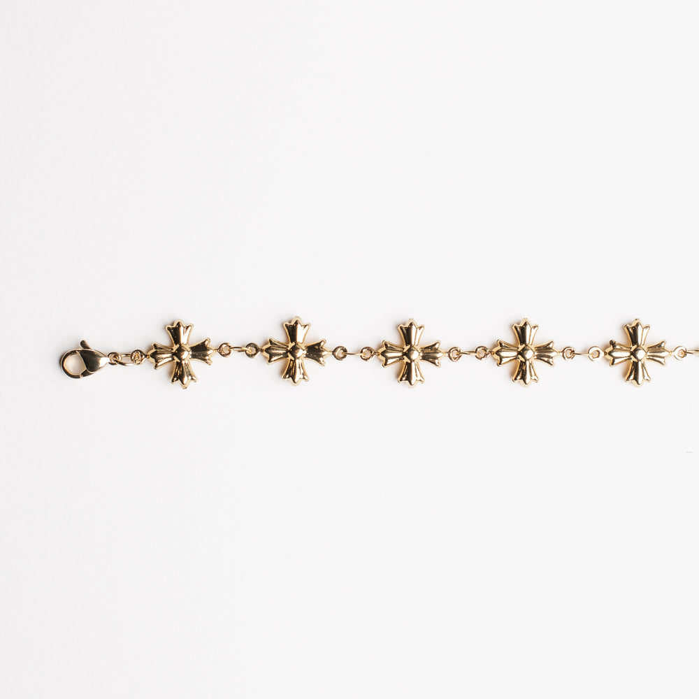 
                  
                    Gold bracelet with cross shaped charms on a white background
                  
                