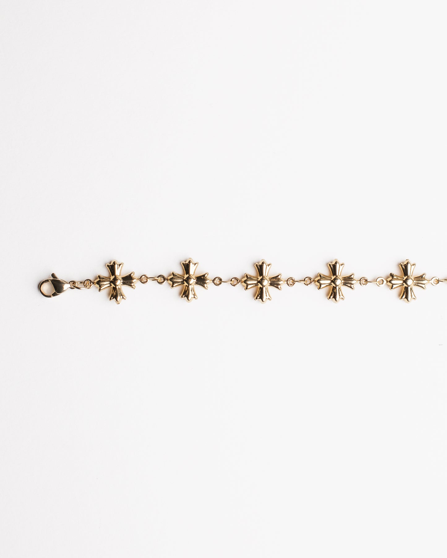 Gold bracelet with cross shaped charms on a white background