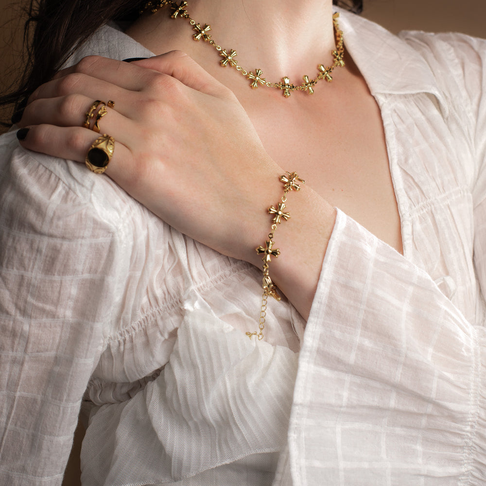 Woman wearing gold jewelry including a vintage necklace, bracelet, and ring on a neutral background