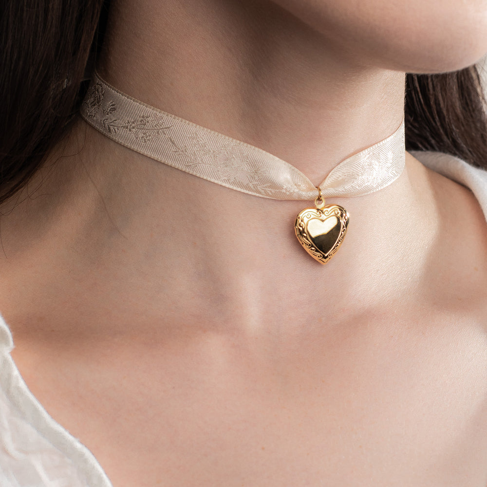 Gold heart shaped pendant on a delicate white ribbon necklace