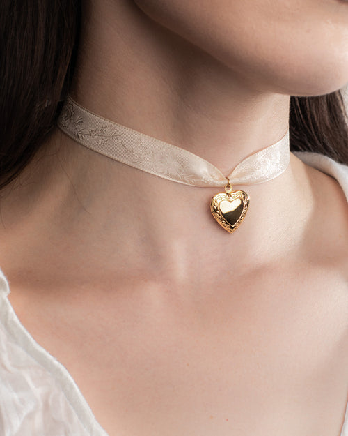 Gold heart shaped pendant on a delicate white ribbon necklace