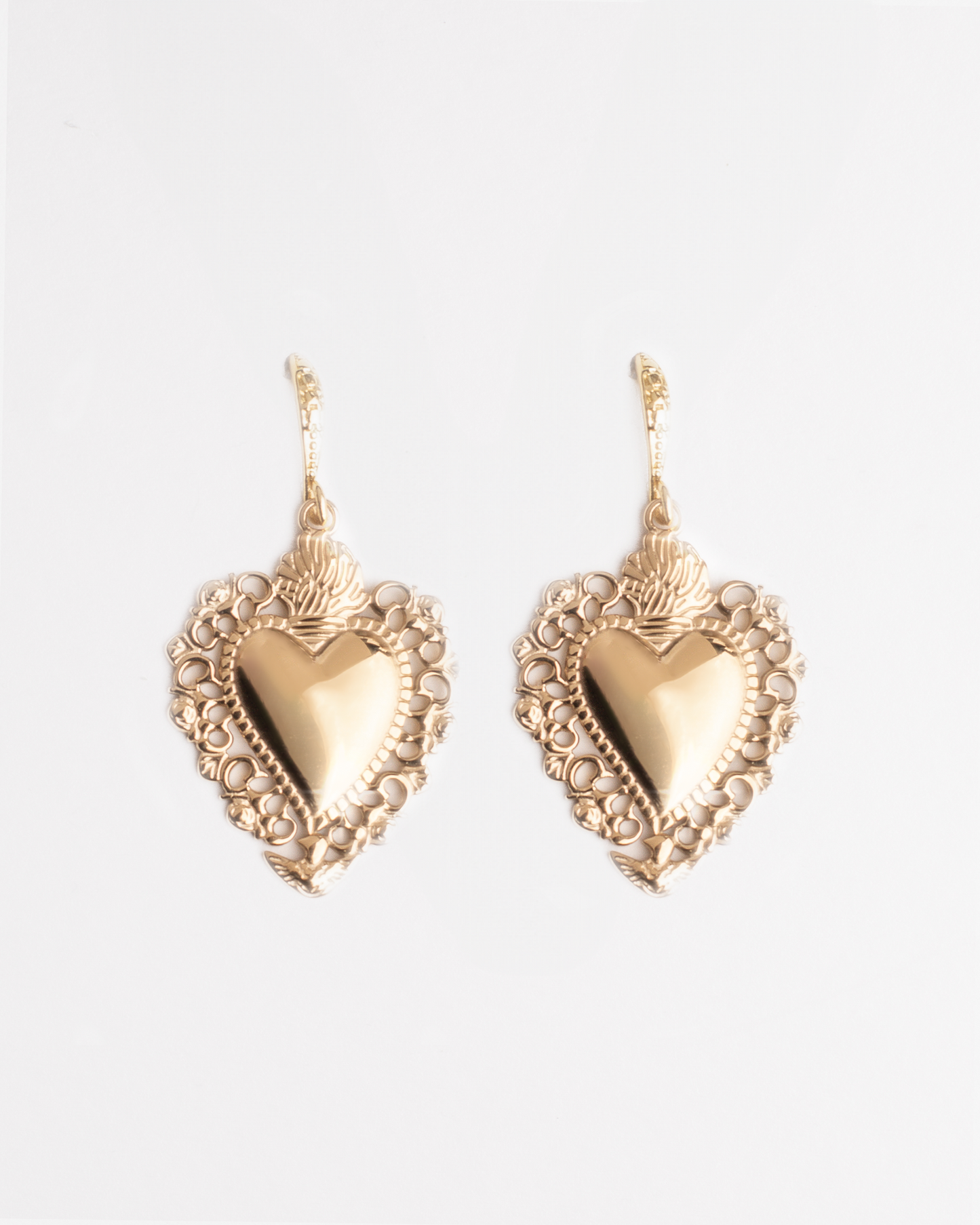 Gold vintage heart shaped earrings on a white background